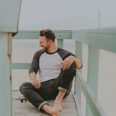 smiling man sitting outdoors baseball tee jeans